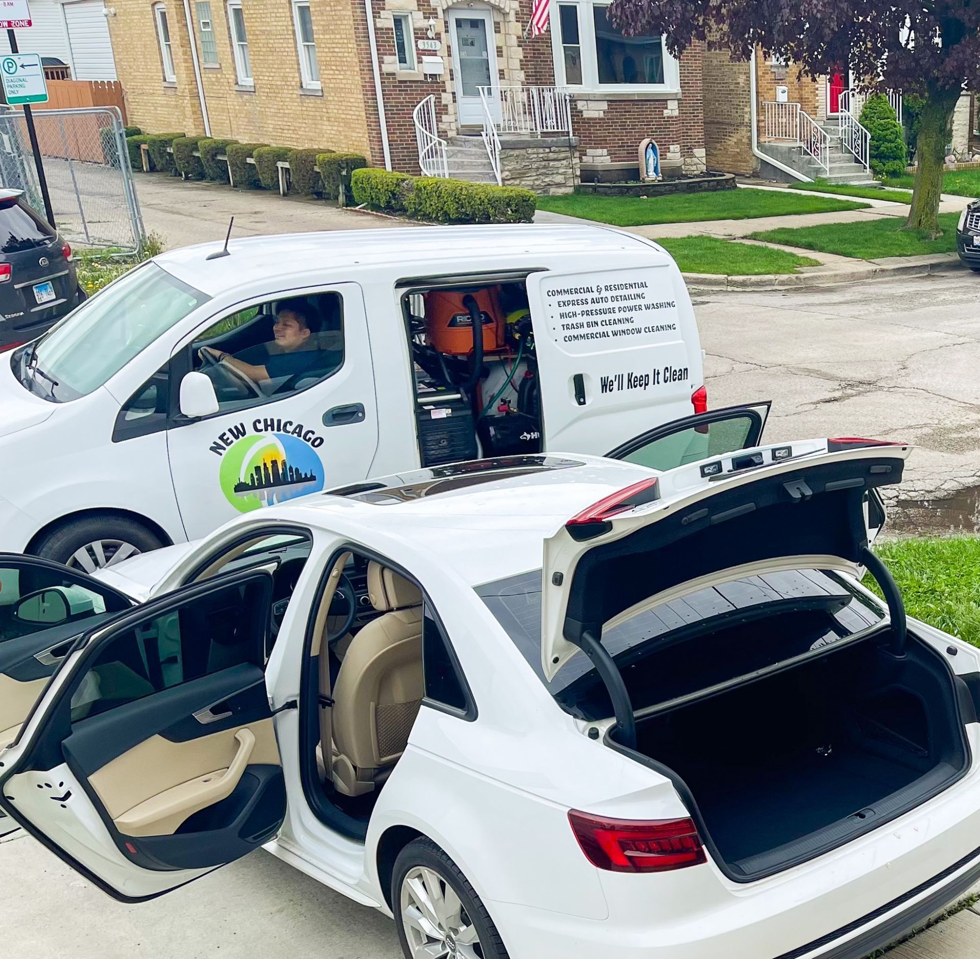 A white car is parked next to a white van that says new chicago