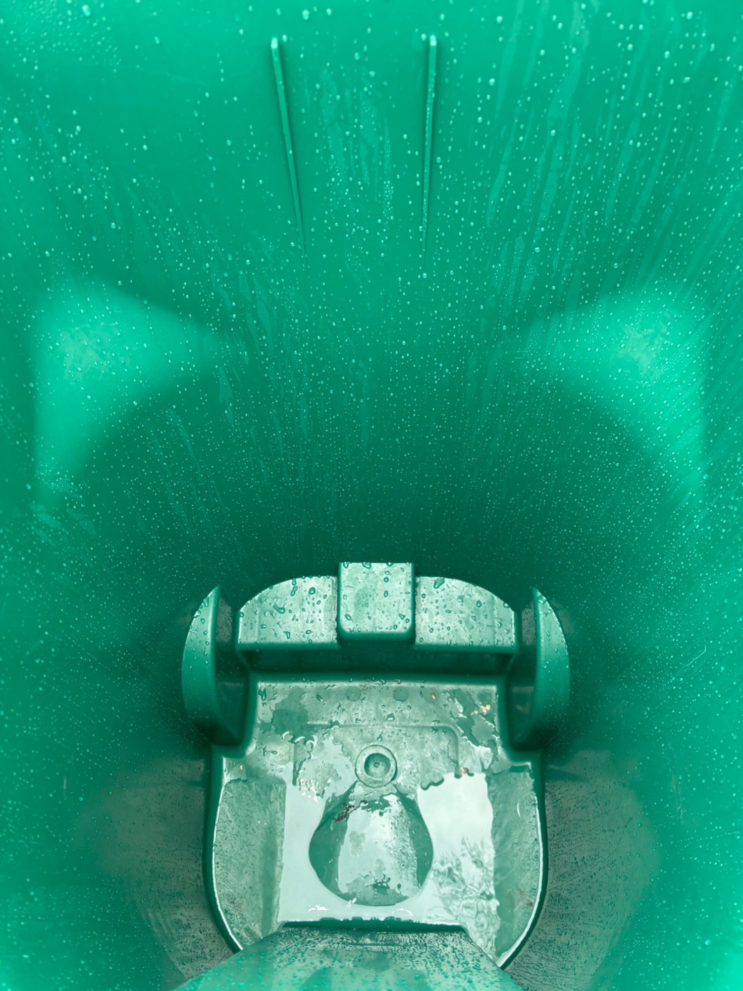 The inside of a green trash can with the lid open