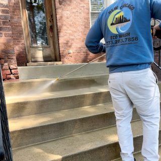 A man in a blue shirt is cleaning the steps of a house.