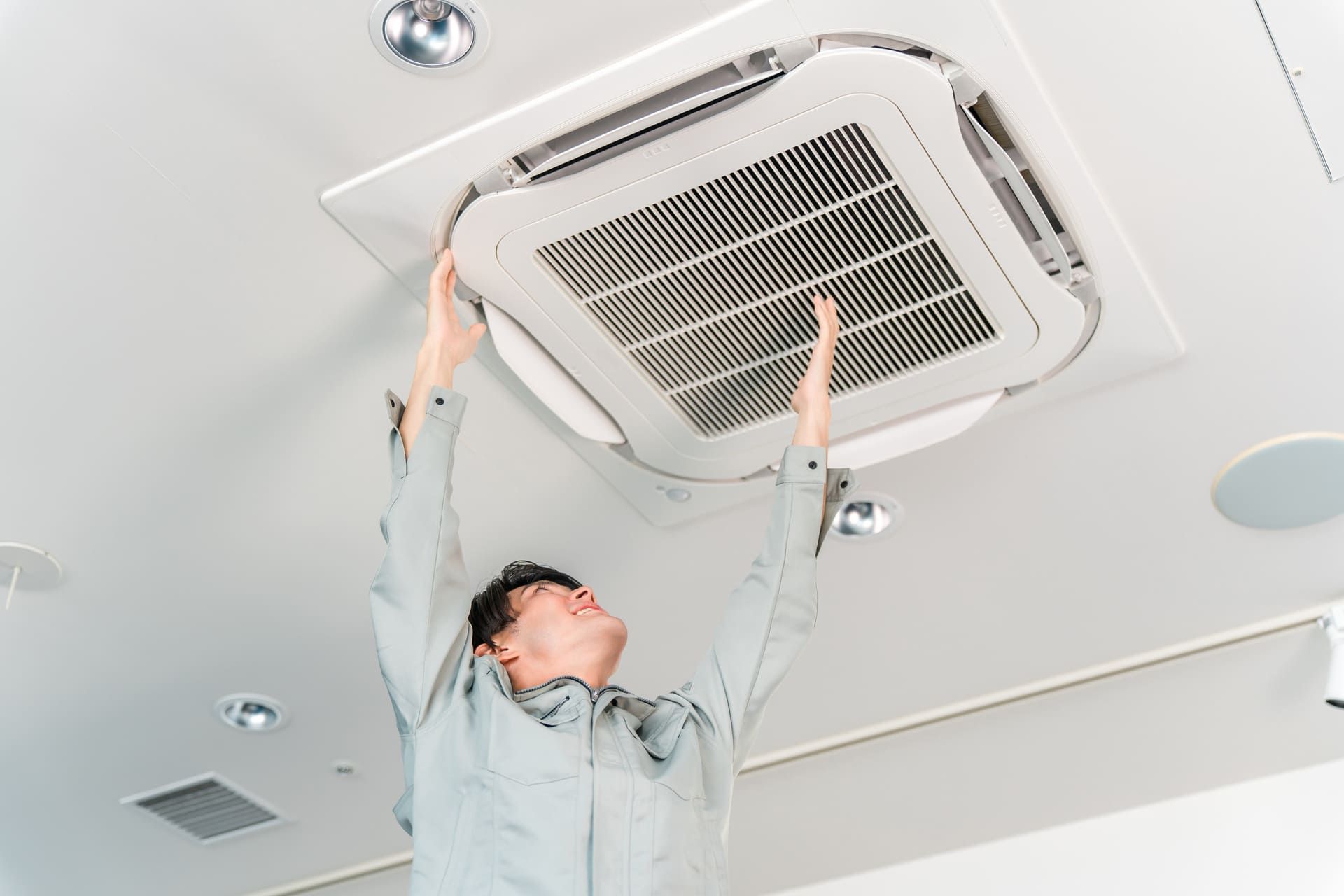 エアコン・空調設備の清掃,点検をする作業着の男性