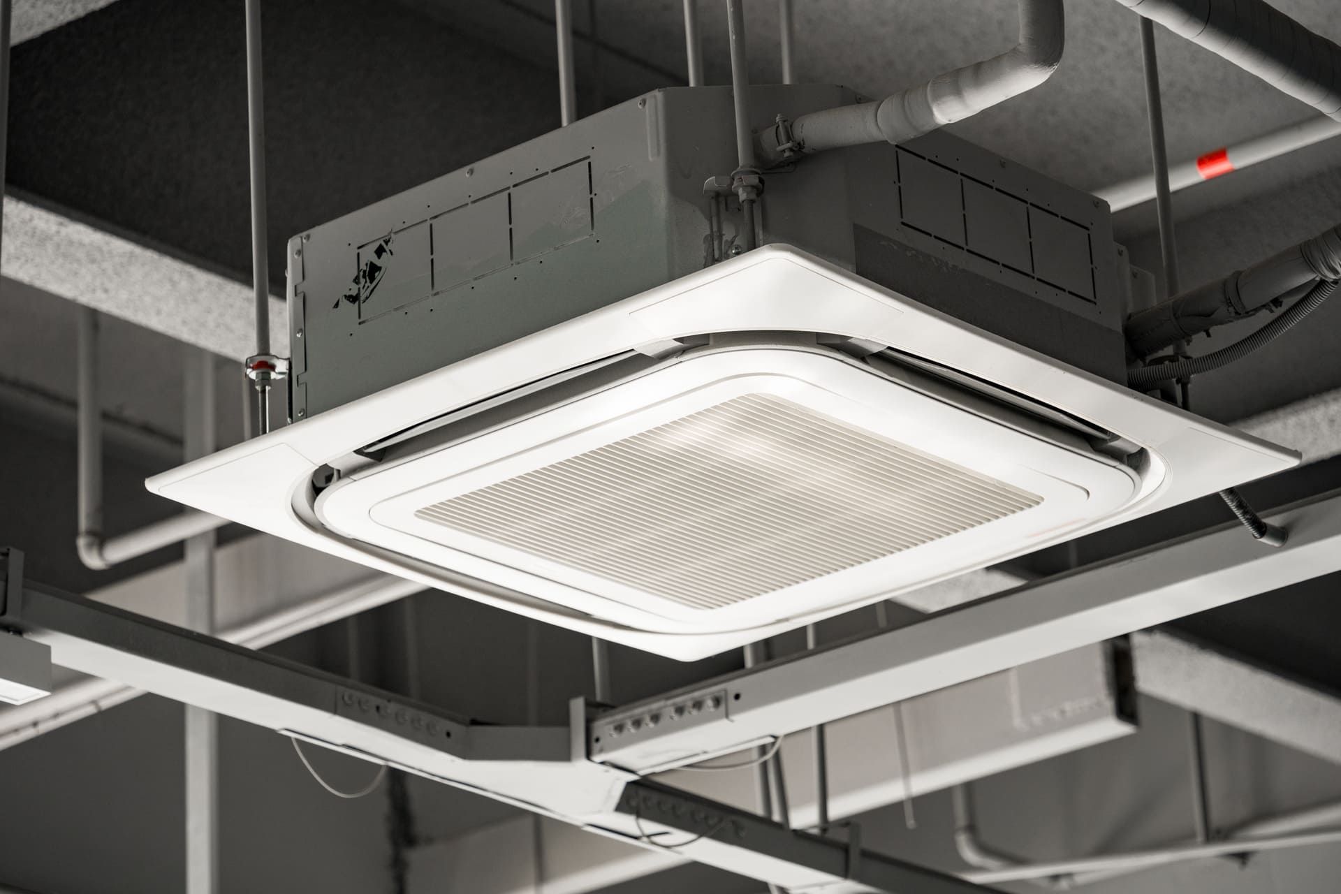 Ceiling-mounted square cassette air conditioning unit with metal grille and ventilation system