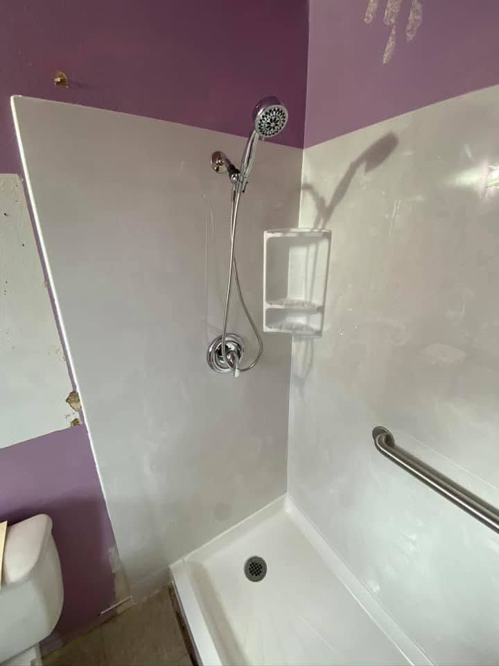 Small bathroom shower with folded shower screen, wall-mounted showerhead, and purple-and-white walls