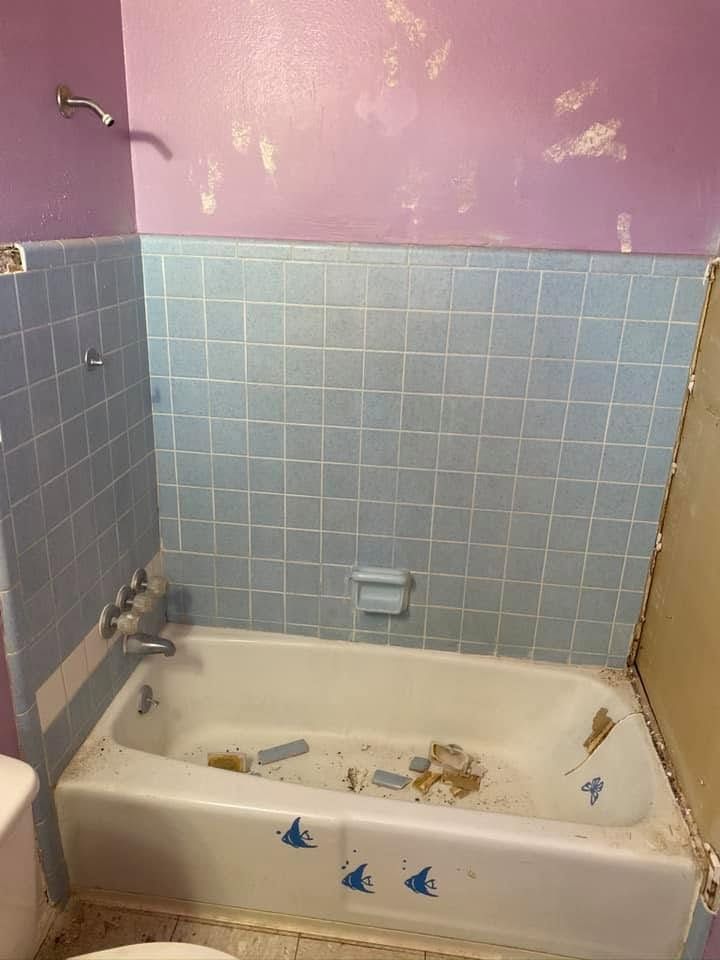 Small bathroom with a worn bathtub, blue tile walls, and a purple painted upper wall.