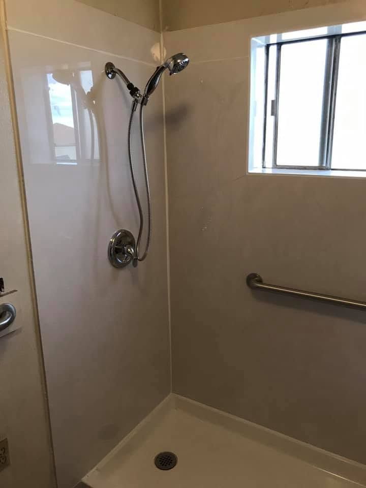 Accessible bathroom shower with grab bar, showerhead, and window