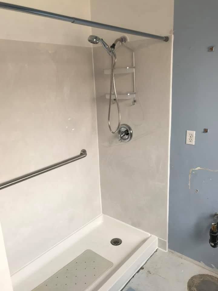 Accessible shower with grab bars, handheld showerhead, fold-down seat, and low curb entry