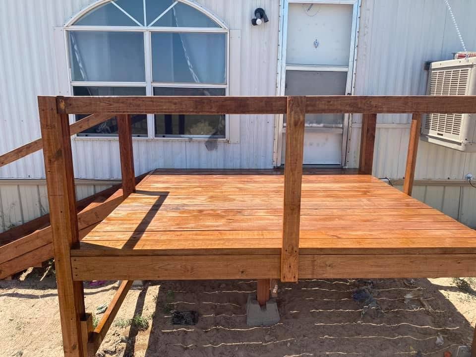 Wooden deck platform with railings beside a white house