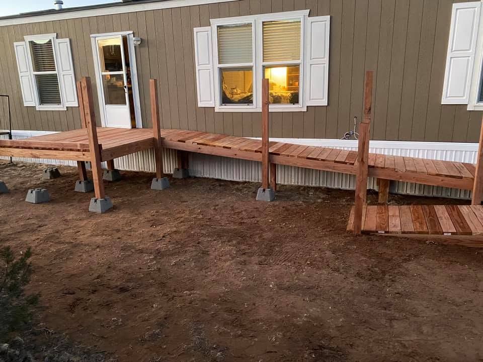 Wooden ramp and deck under construction beside a house with white windows and beige siding