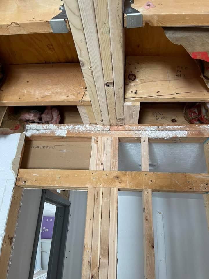 Unfinished interior wall framing with exposed insulation and a doorway opening underneath