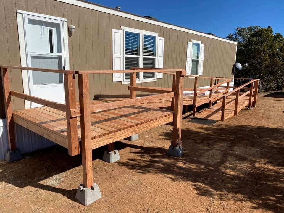 Wooden accessibility ramp with railings leading to a beige mobile home entrance