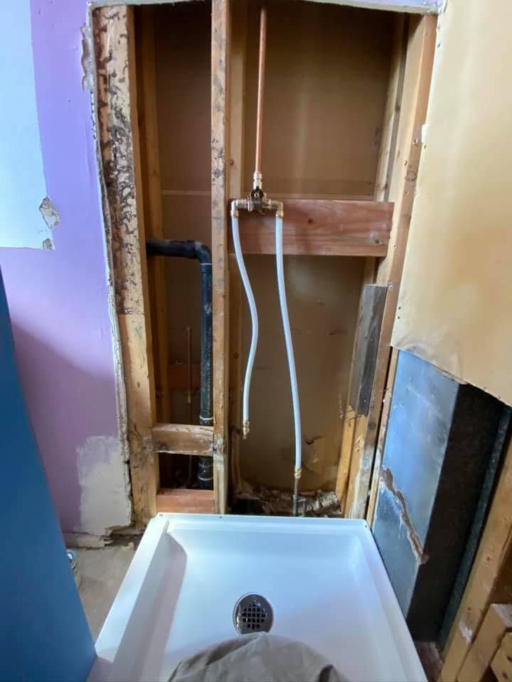 Bathroom under renovation with exposed plumbing behind a white sink.