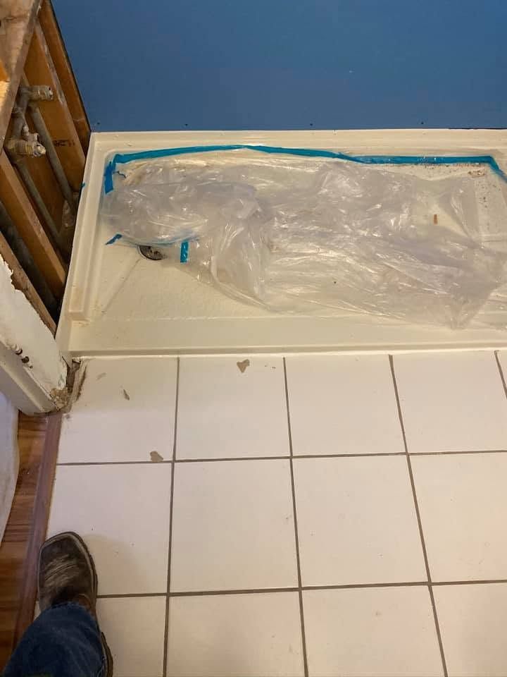 Clear plastic-wrapped item lying on a tiled floor beside a door and wooden furniture.