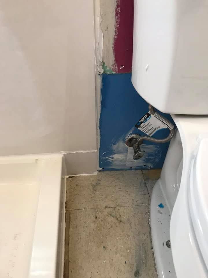 Partially finished bathroom wall with exposed plumbing beside a toilet and tub/shower area