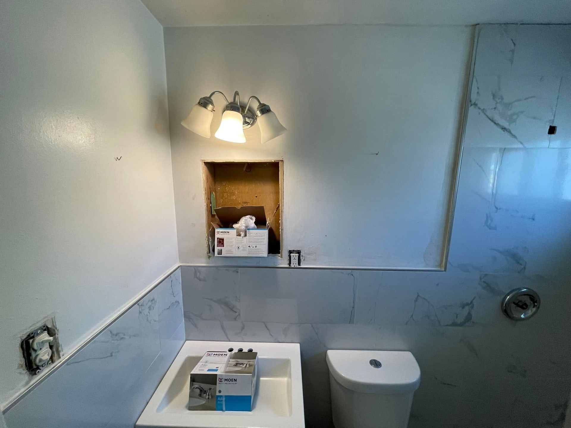Tiled bathroom with vanity sink, toilet, and wall mirror lit by two sconces.