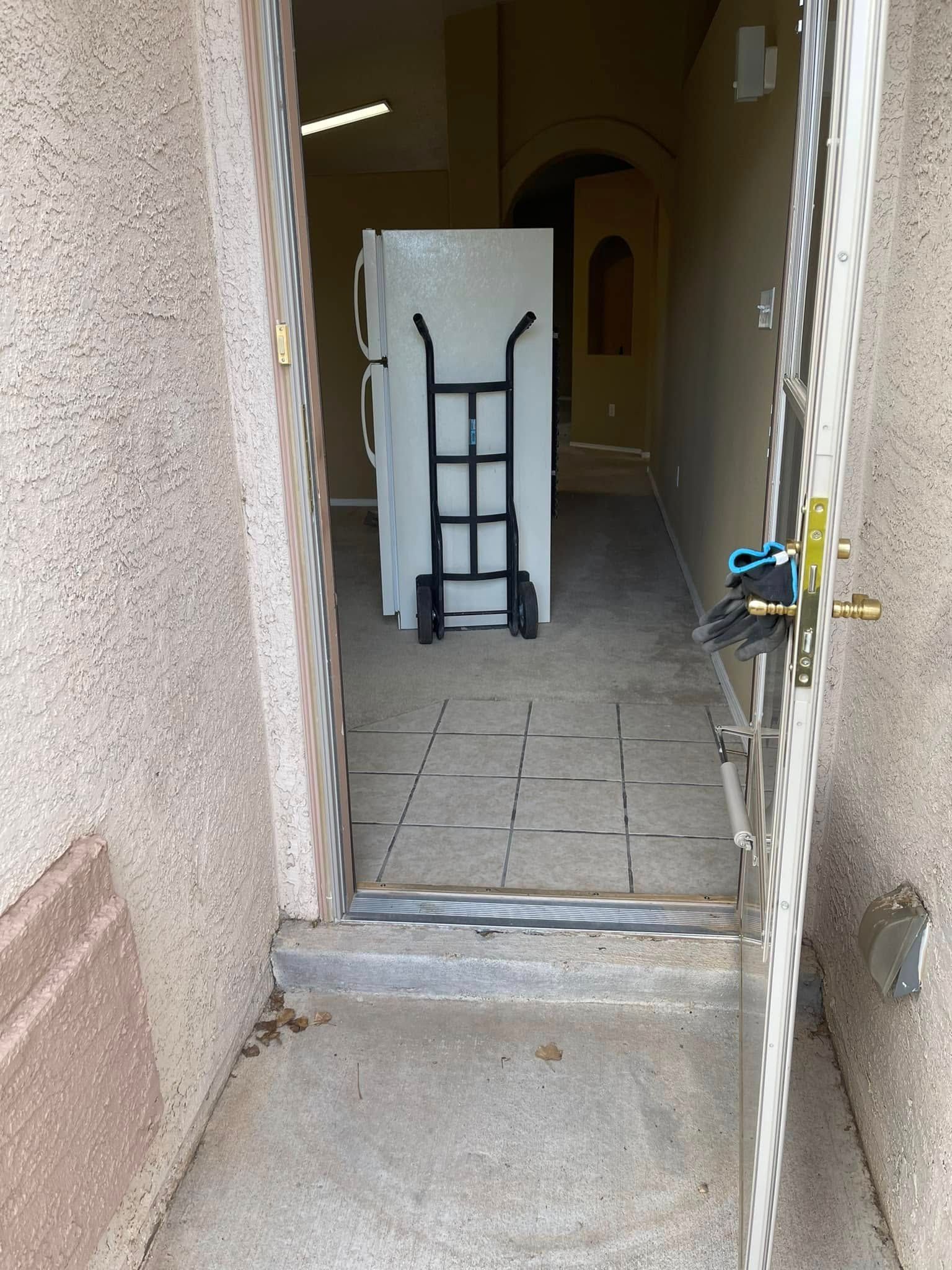 Open doorway to a tiled entryway with a folding hand truck inside