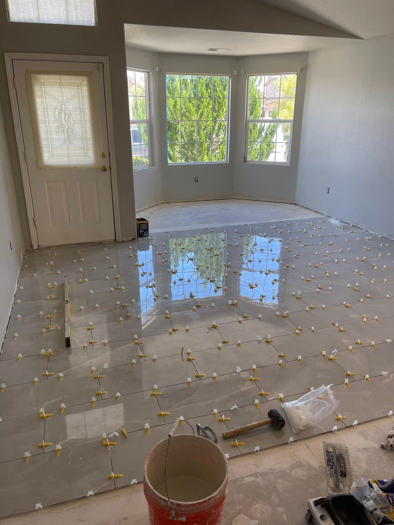 Empty room with tile floor covered in reflective spill, white walls, and large windows.