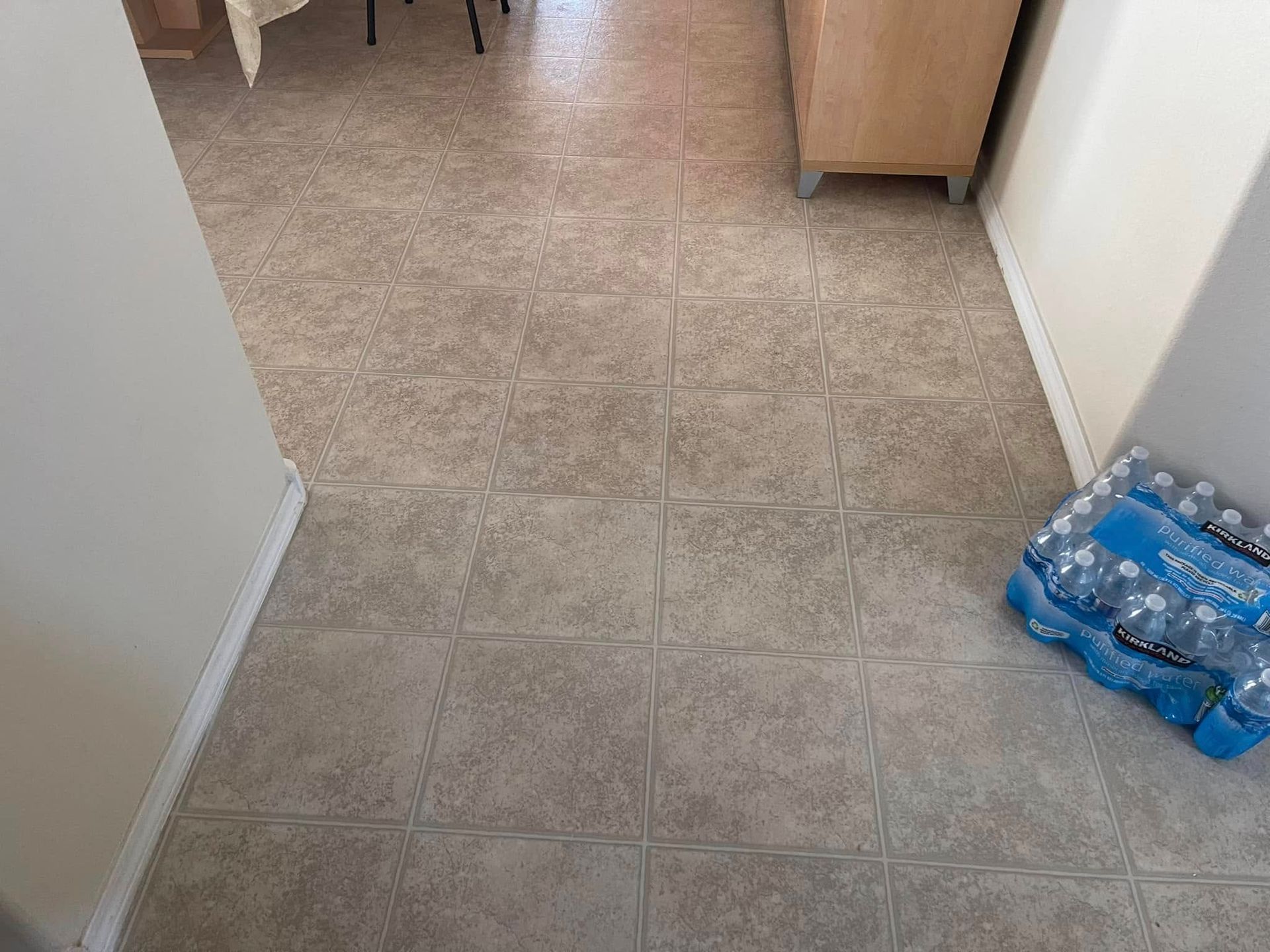 Carpeted hallway with a pack of bottled water on the right side near a doorway.