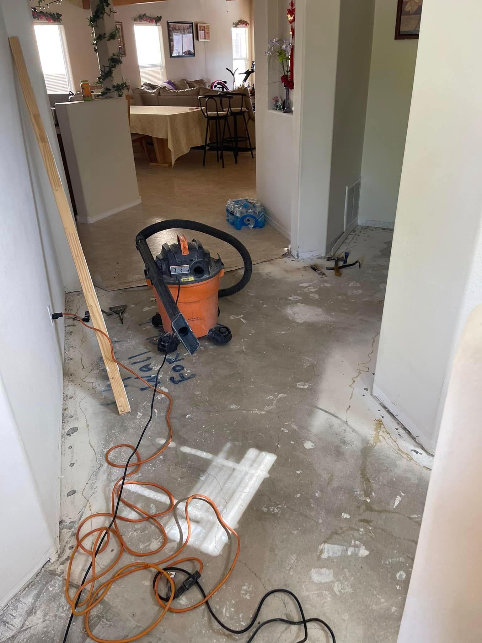 Hallway under renovation with scattered tools, vacuum, cords, and dust on the floor