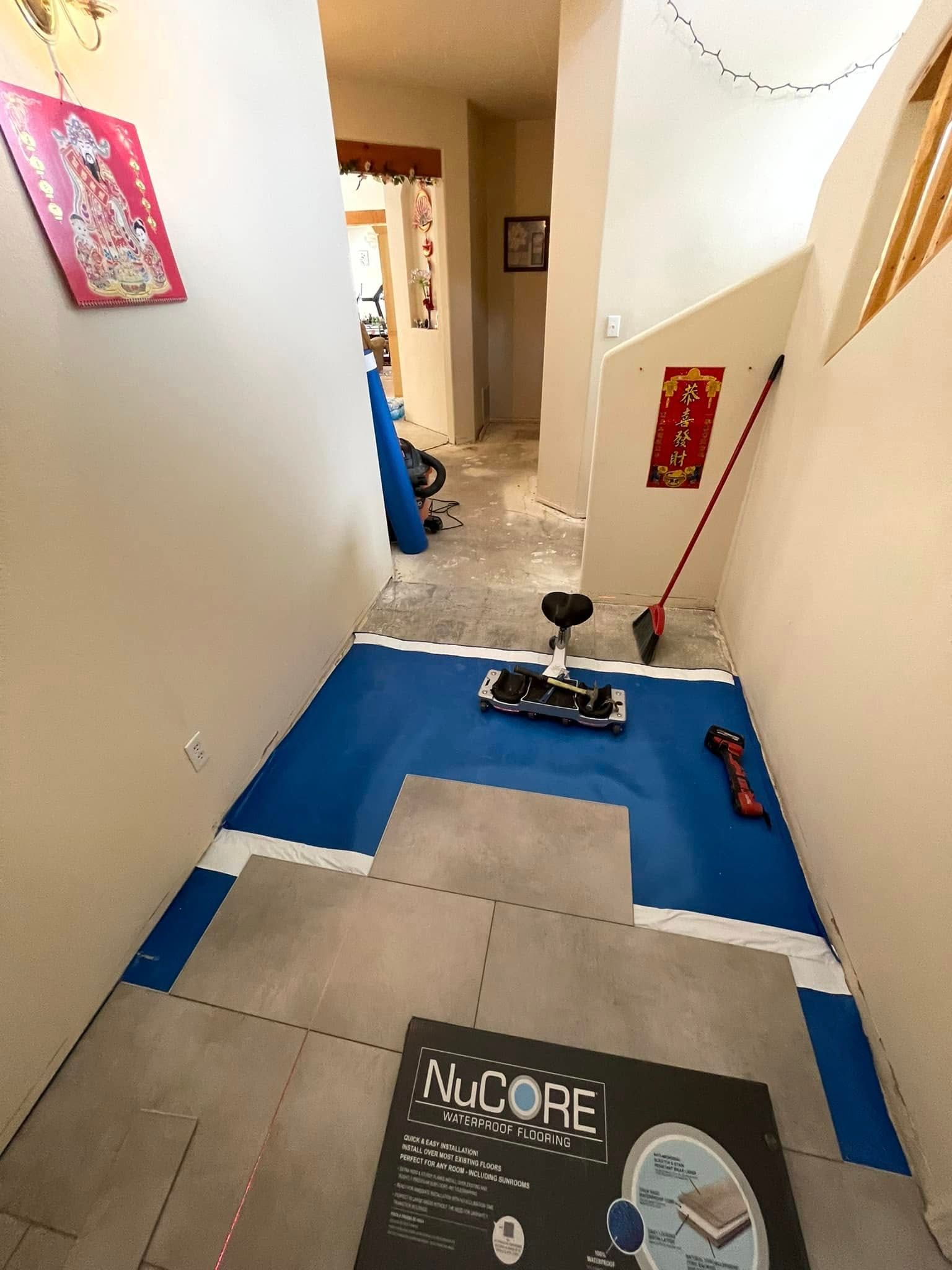 Narrow hallway with blue floor covering, scattered items, and stairs on the right.