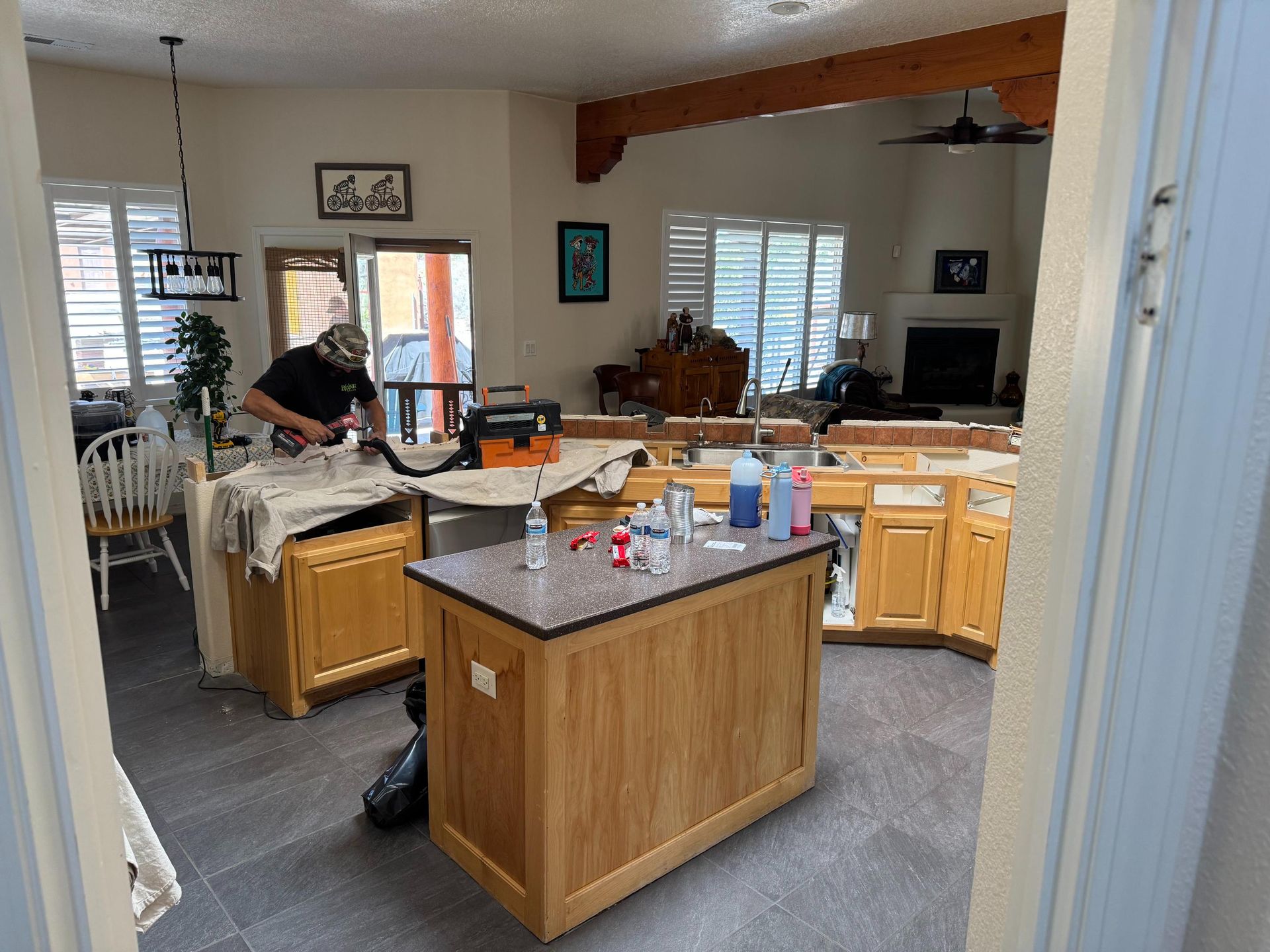 Kitchen with an island, cabinets, and a person cleaning near the counter.