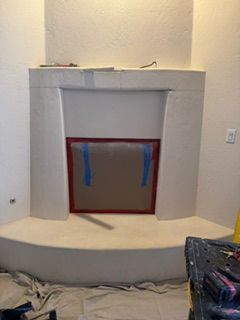 Gray fireplace under construction with taped red-framed opening and unfinished wall surround