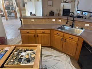 Kitchen with wood cabinets, stainless sink, and countertop work area covered in protective plastic.
