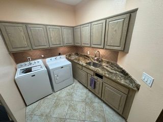 Small laundry room with washer, dryer, and beige cabinets along a granite countertop.