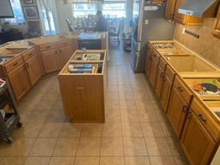 Bright kitchen with wooden cabinets, tiled floor, central island, and sink by a window.