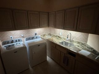 Dimly lit L-shaped kitchen with white appliances, dark wood cabinets, and granite countertop.