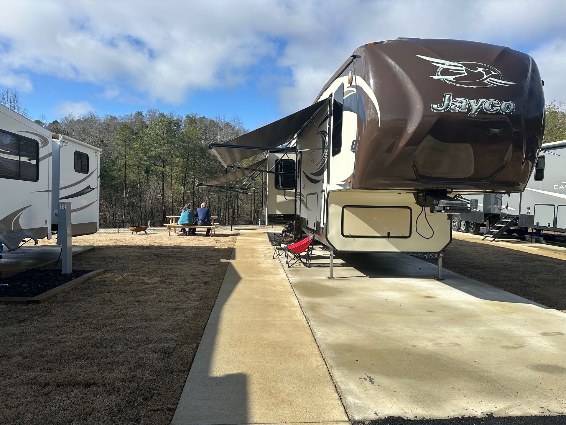 A group of people are sitting at a picnic table in front of a trailer.