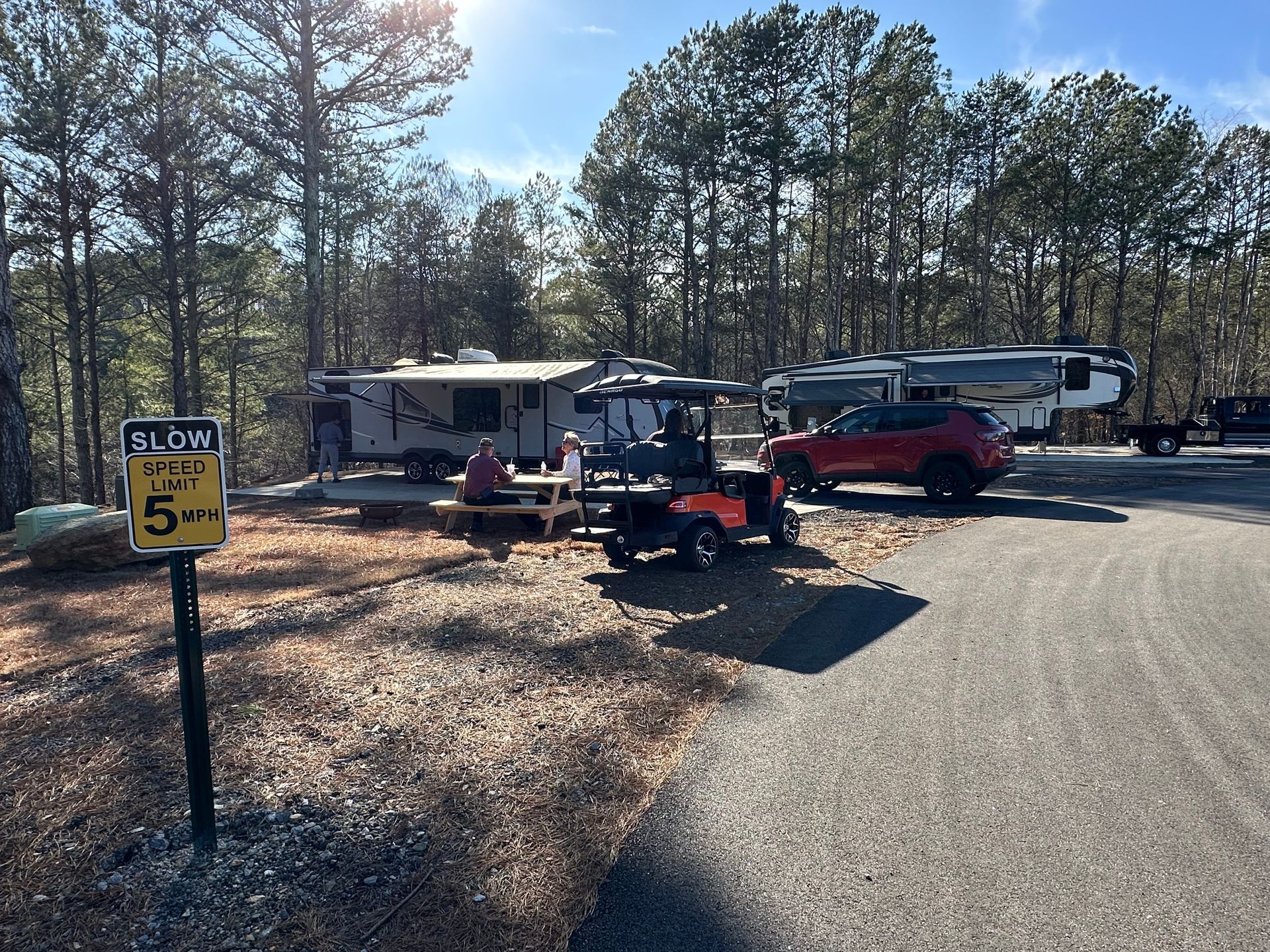 A rv with an awning is parked in the middle of a forest.