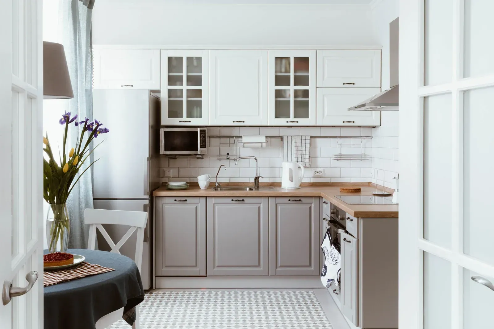 Small kitchen with gray and white cabinets, wooden countertops, and a white tile backsplash.