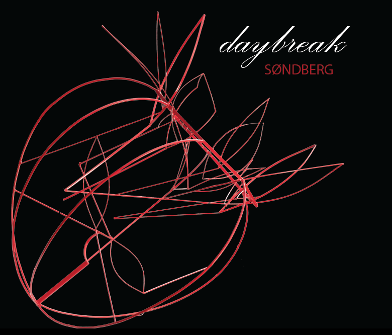 A woman wearing a black t-shirt and gray pants is standing in front of a stone wall.