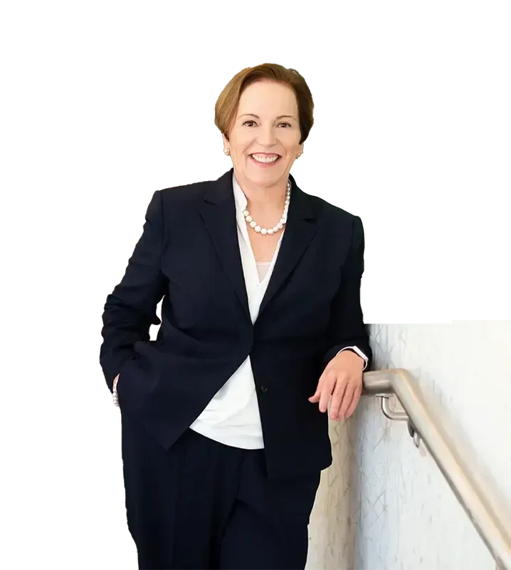 A woman in a suit is leaning on a railing and smiling