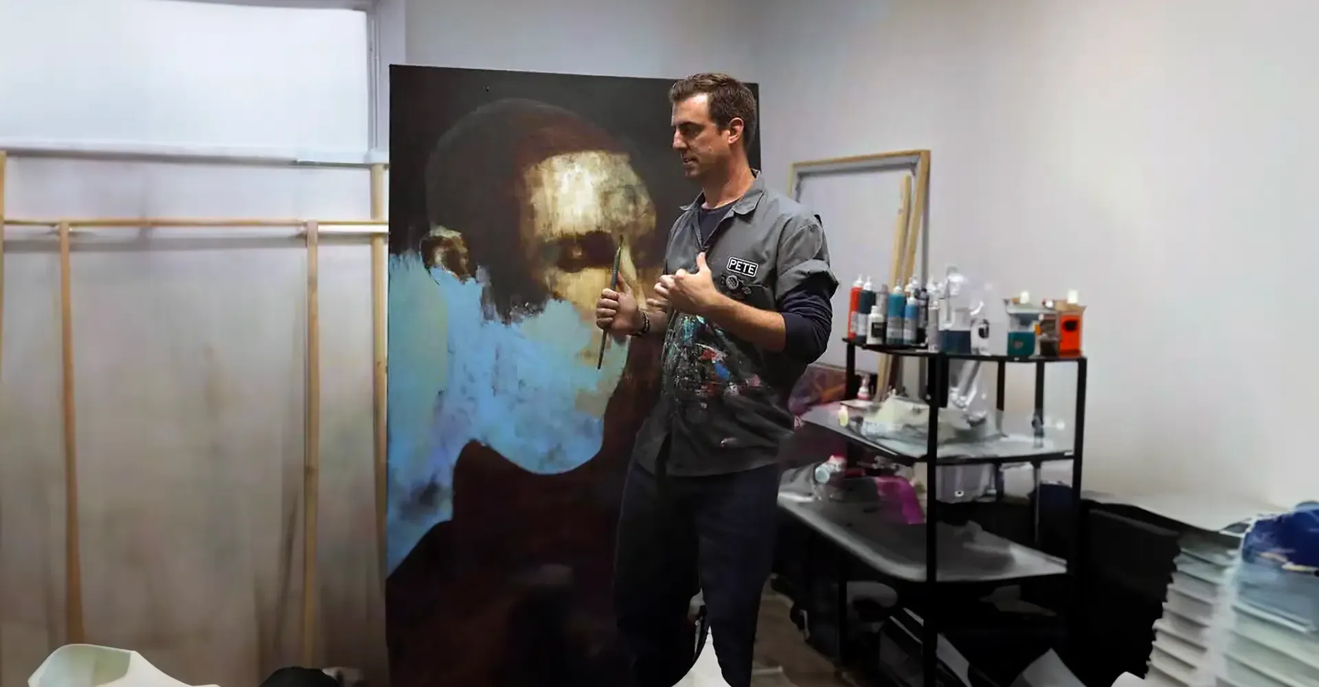 A man is standing in front of a large painting