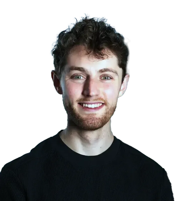 A young man with a beard is wearing a black sweater and smiling.