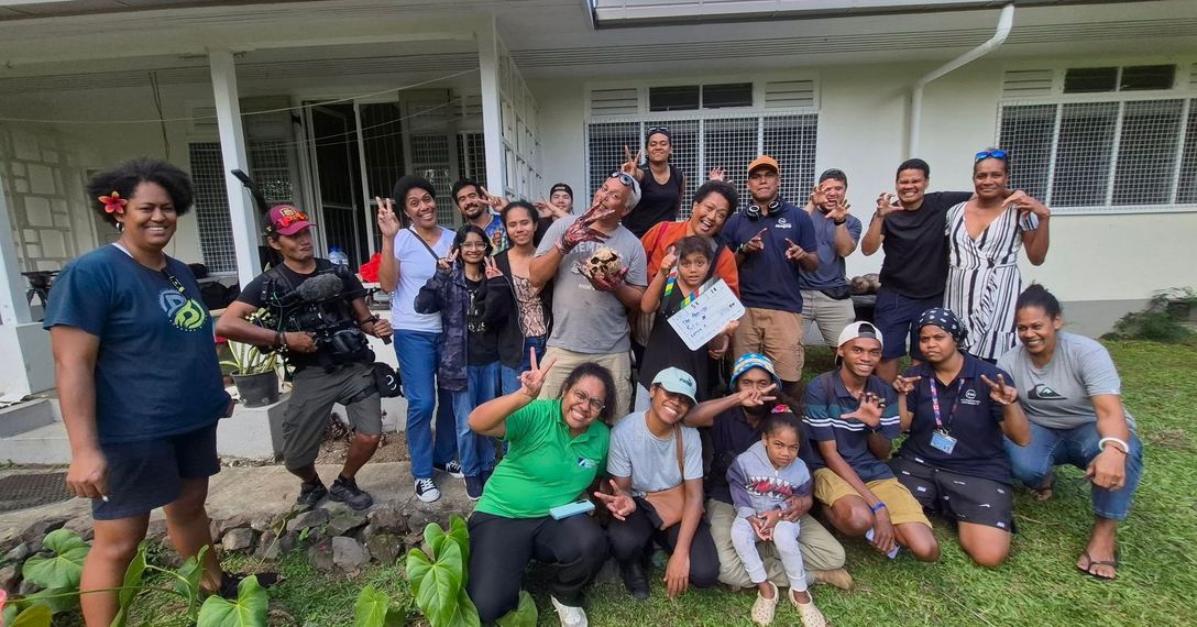 Group of diverse people smiling and posing outdoors in front of a building.
