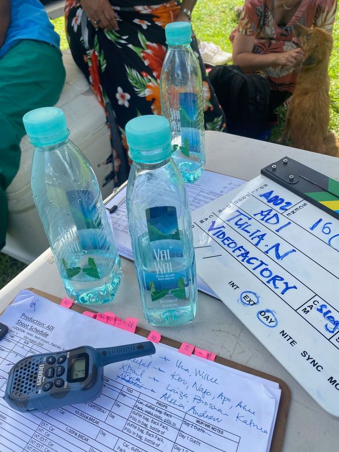 Bottled water, a walkie-talkie, and a clapperboard on a table, likely a film set.