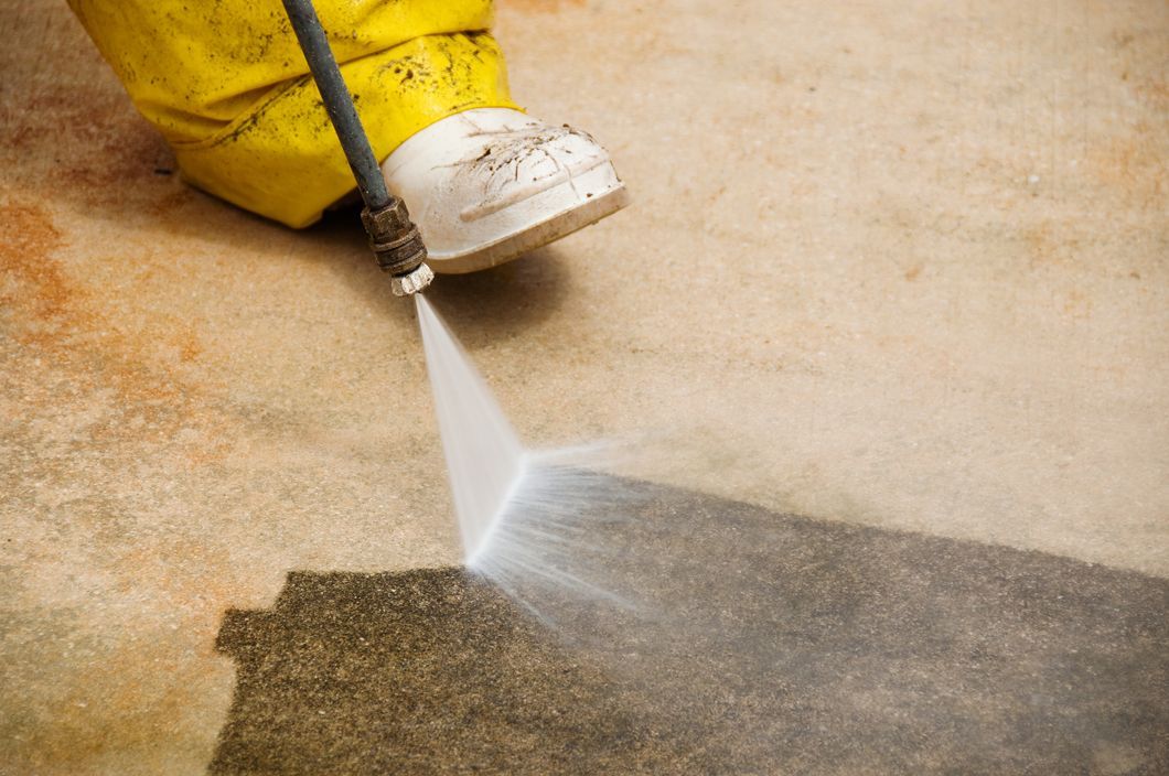 Yellow pressure washer cleaning a concrete surface, spraying a strong stream of water