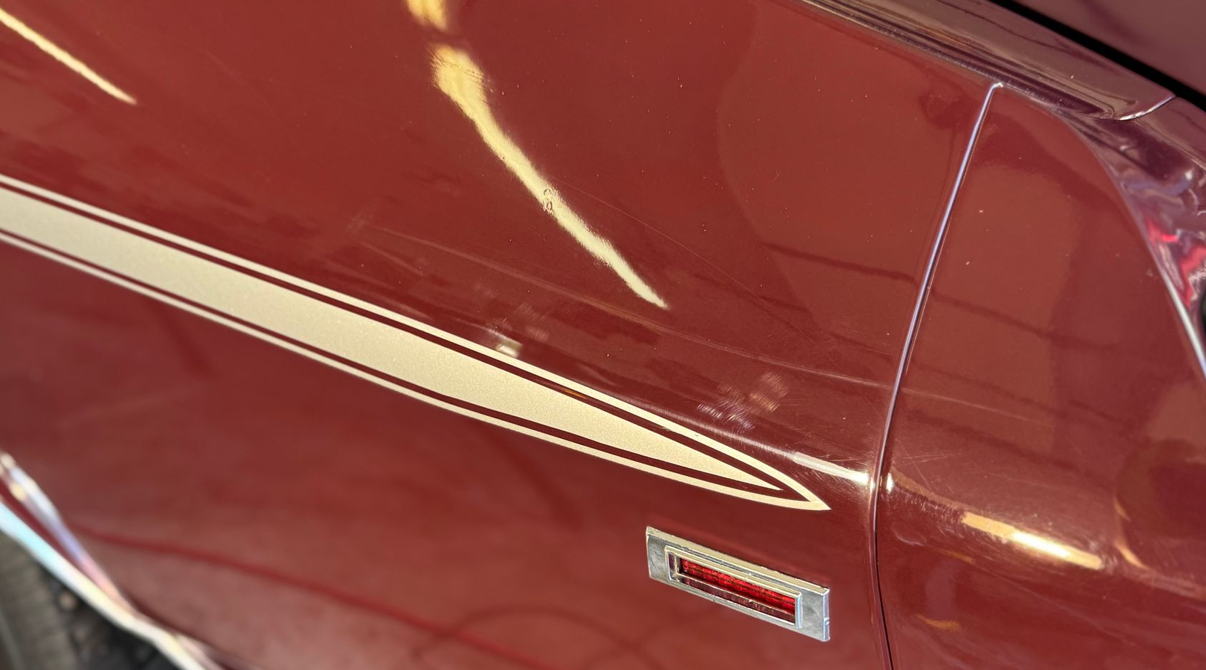 Maroon car fender with white and gold stripe decal; 