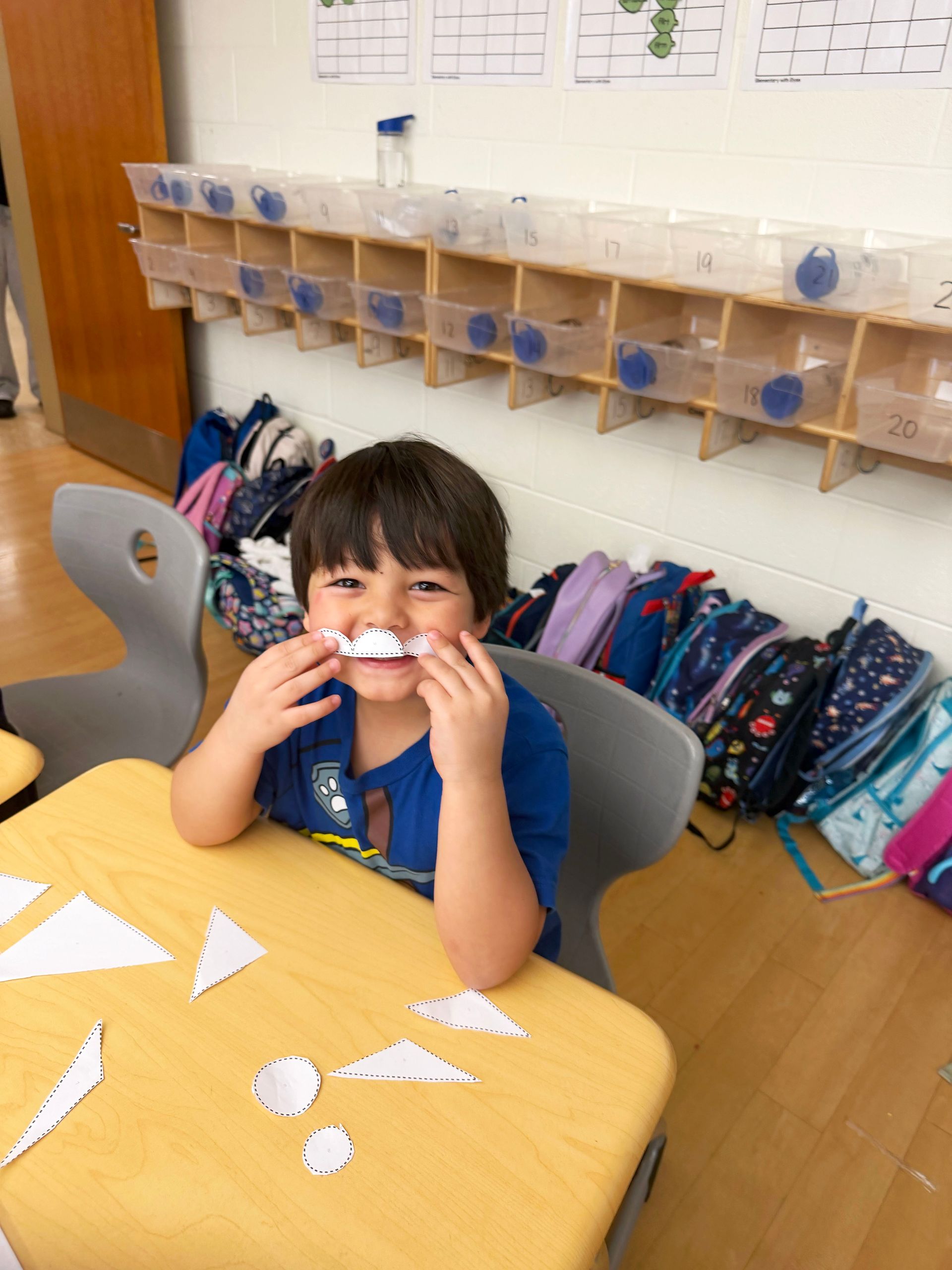 Girl seated on couch, using laptop, smiling. White wall and large window in background.
