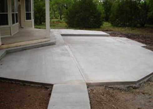 Concrete patio and ramp beside a house, leading from a doorway to a yard path