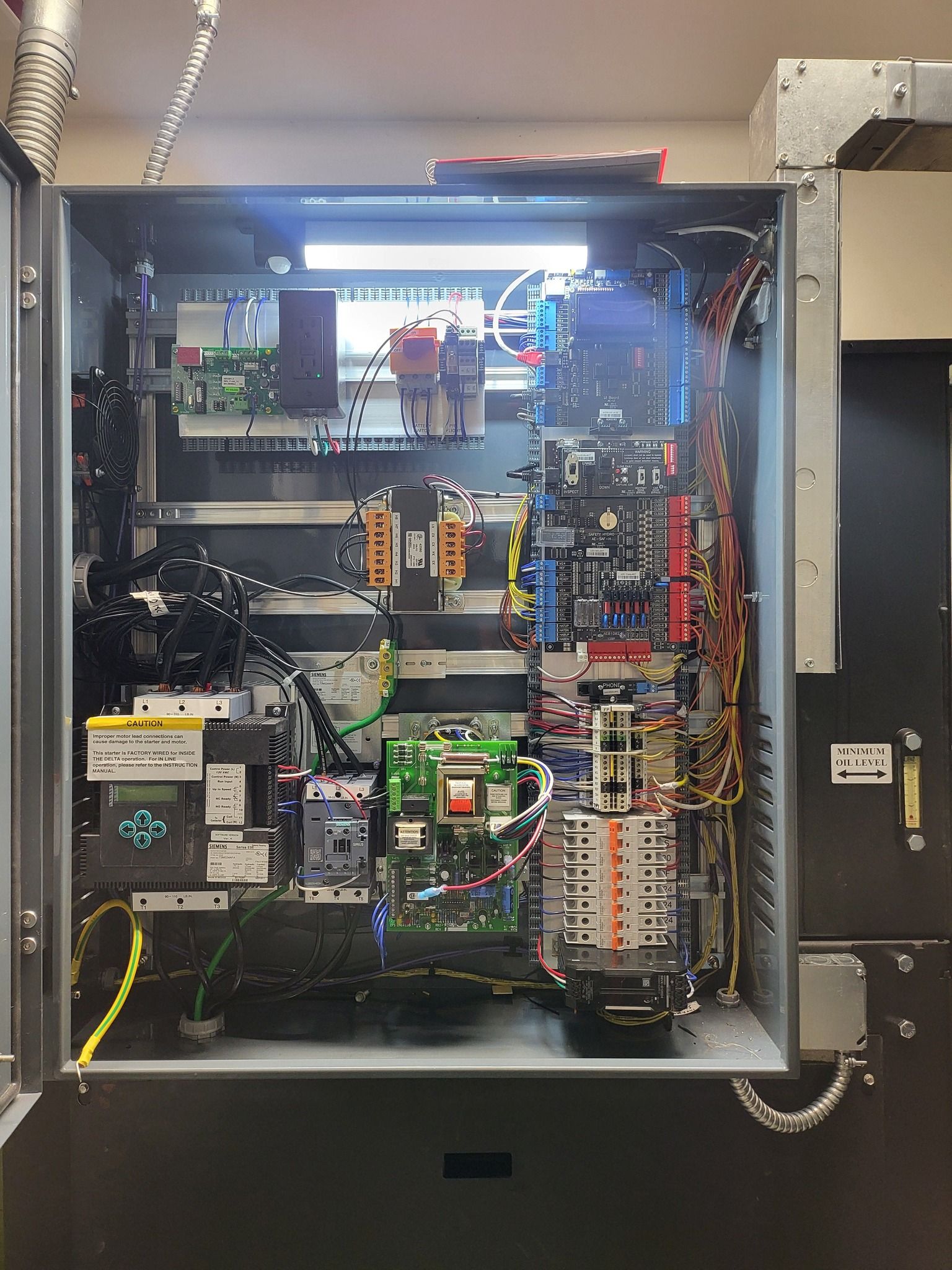 Open electrical control panel with circuit boards, wiring, and components inside a metal cabinet