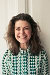 A woman is smiling and wearing a green and white shirt. SEO business