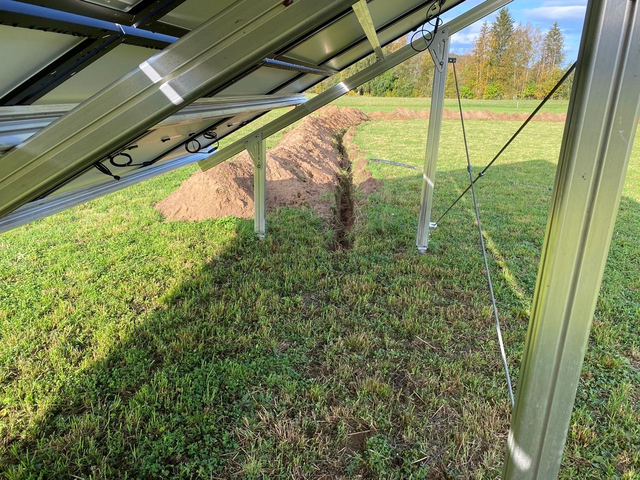 A solar panel is sitting in the middle of a grassy field.