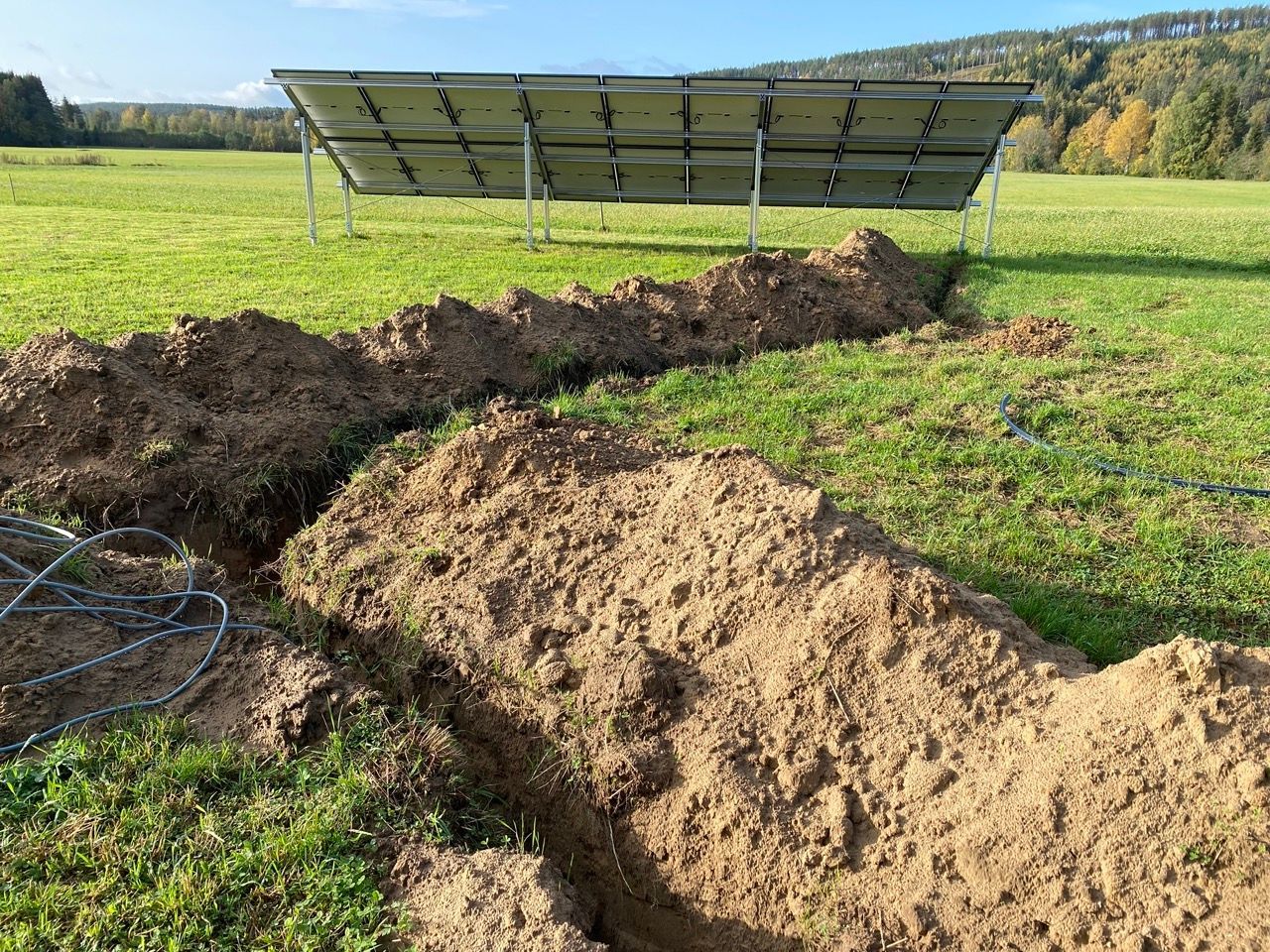 A solar panel is sitting in the middle of a grassy field.