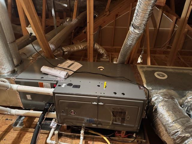 HVAC unit in an attic with ductwork, electrical wiring, and wooden beams.