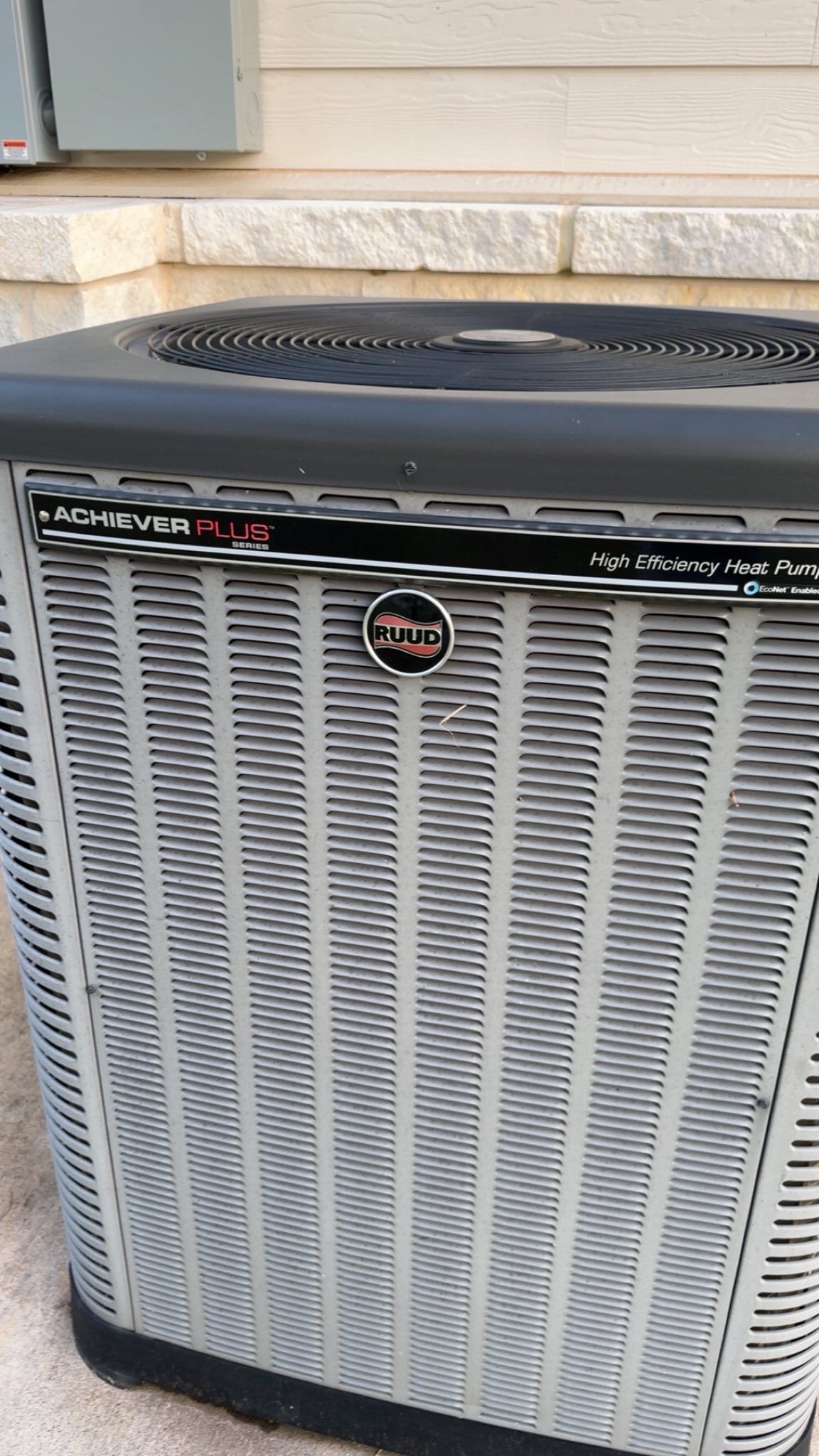 Gray and black Trane air conditioning unit outside on a concrete surface.