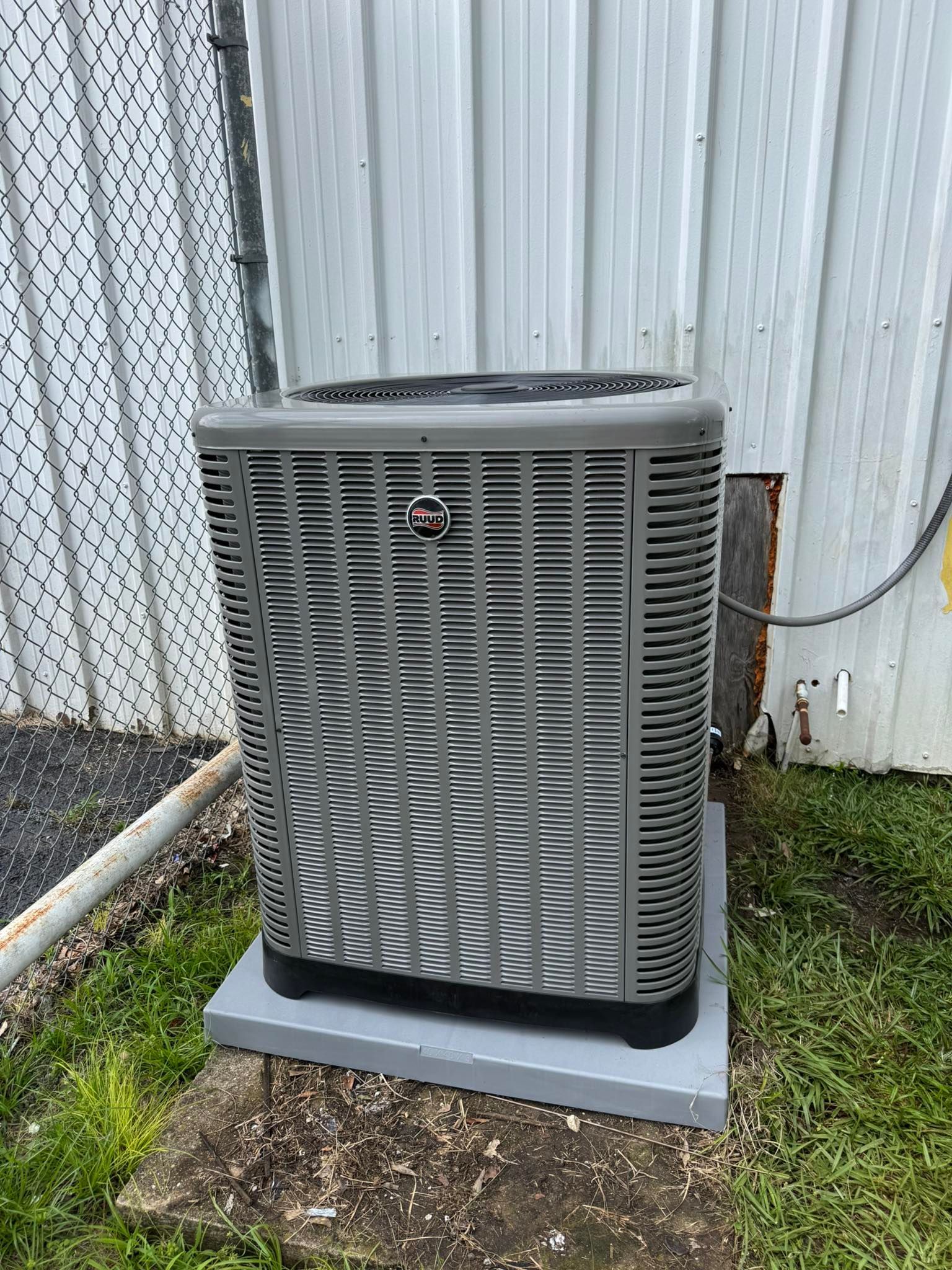 Gray HVAC unit next to a corrugated metal building, sitting on a concrete pad.