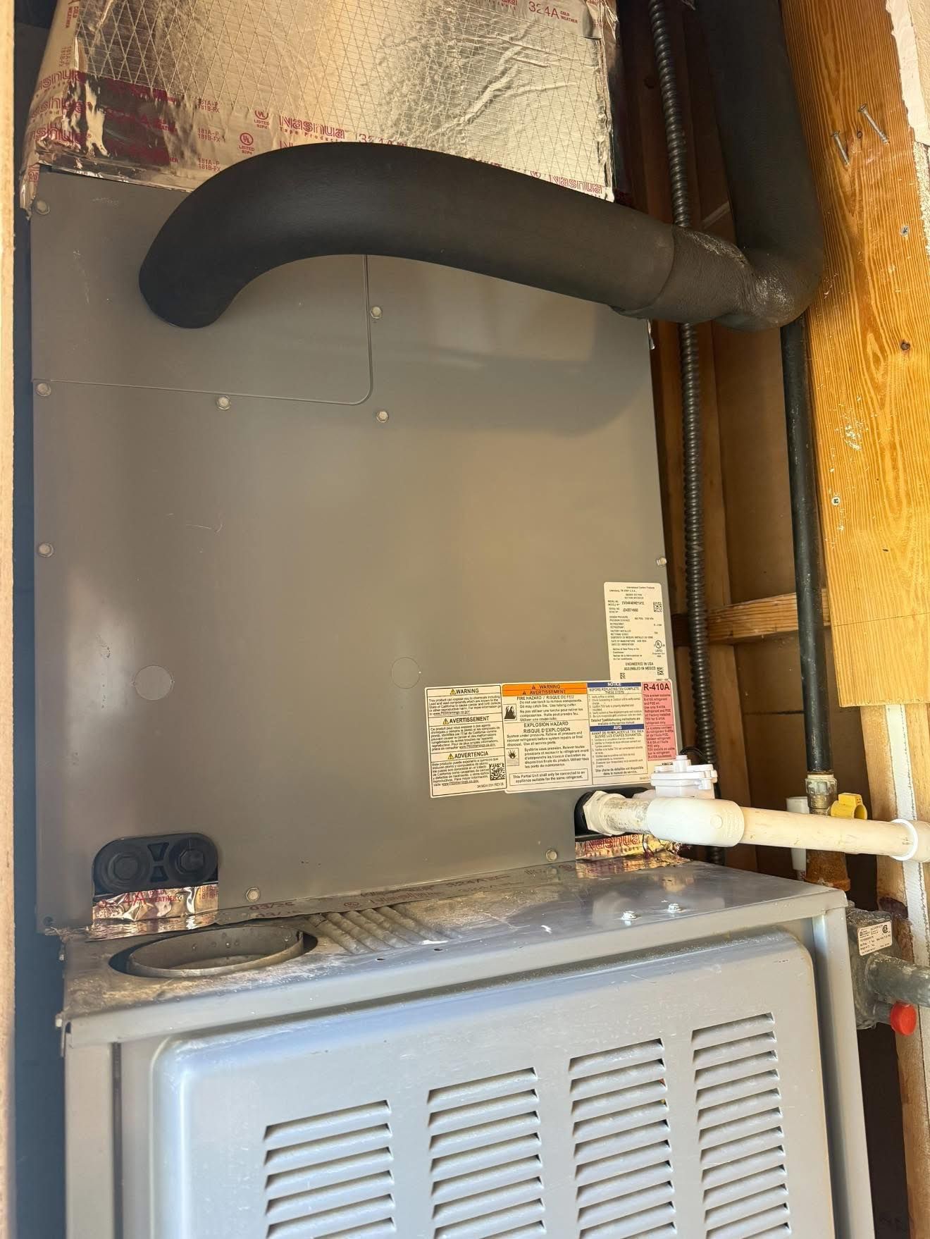 Furnace in a utility room; gray metal with black flue, white pipe, and yellow gas line.