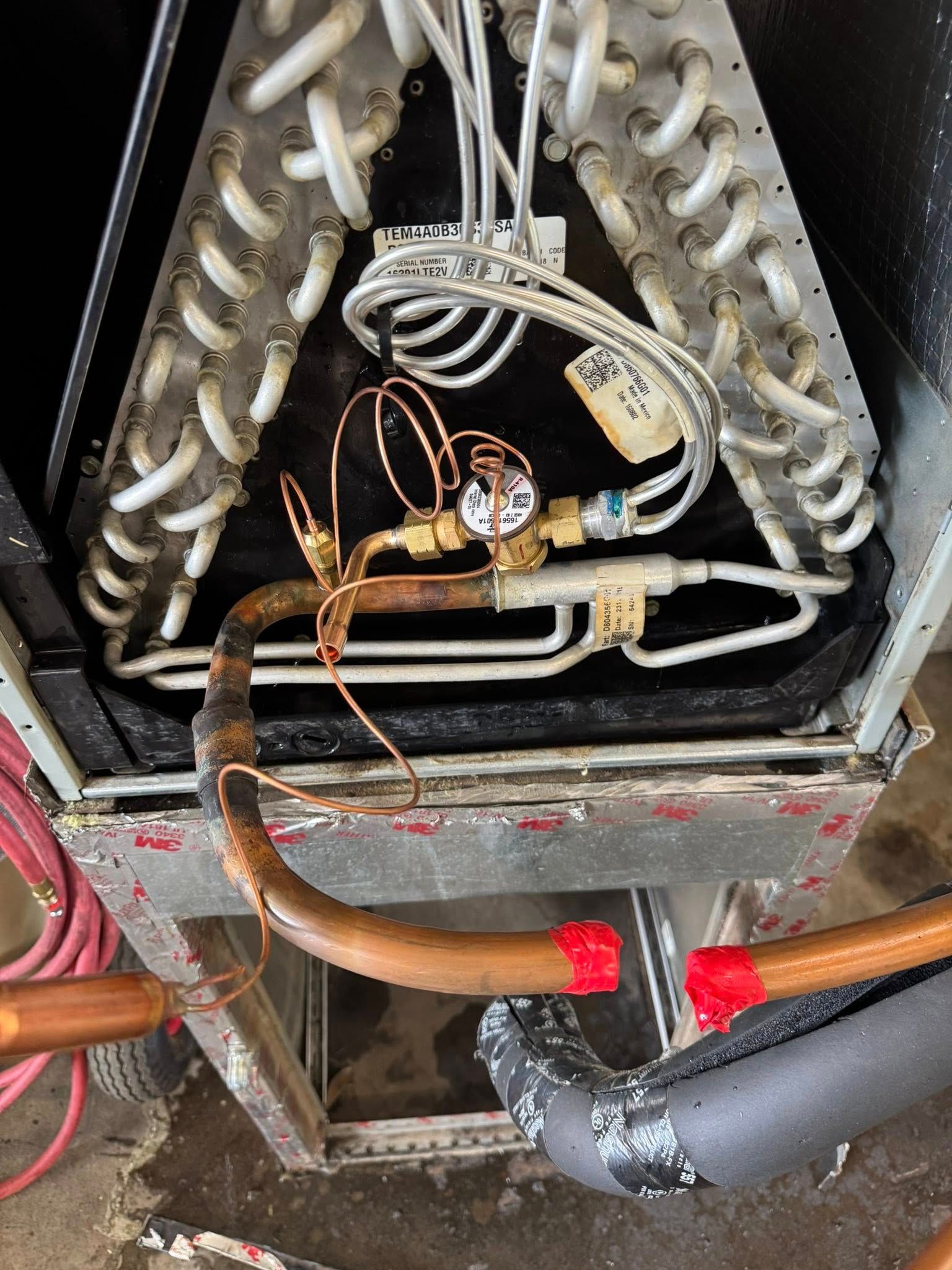 Open air conditioning unit with copper coils, piping, and insulation.